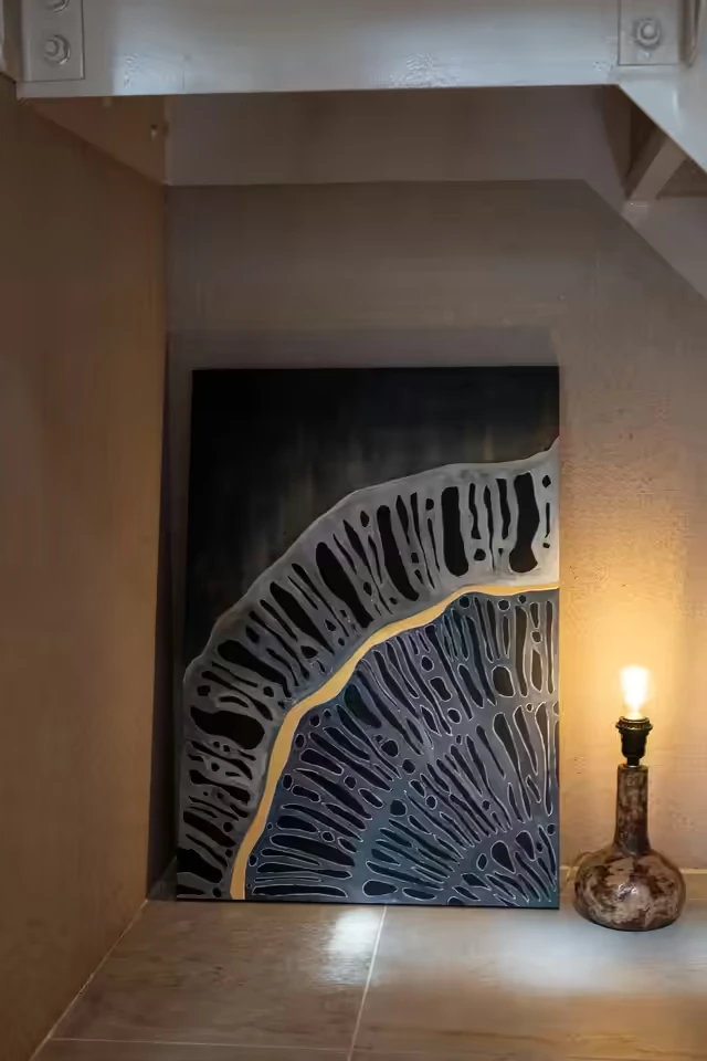 黒地に銀の網目と一筋の金が走る林宜蓁の作品。階段下の展示風景
