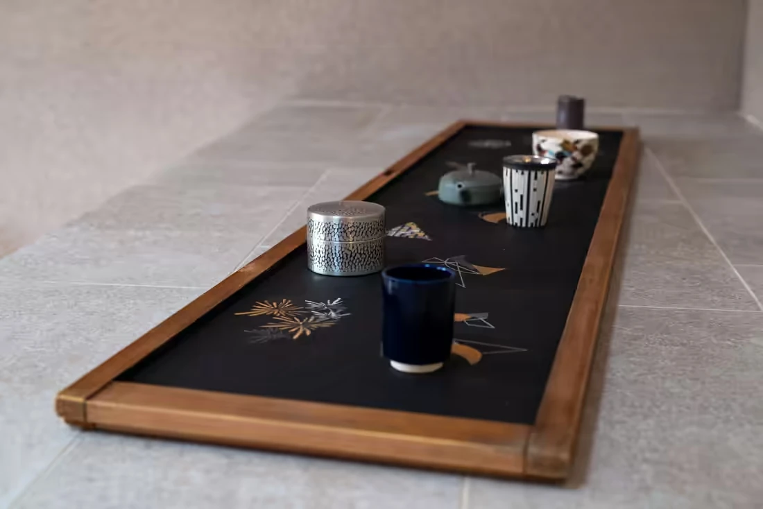 黒地に金銀の文様が描かれた盆と、器を並べた展示風景